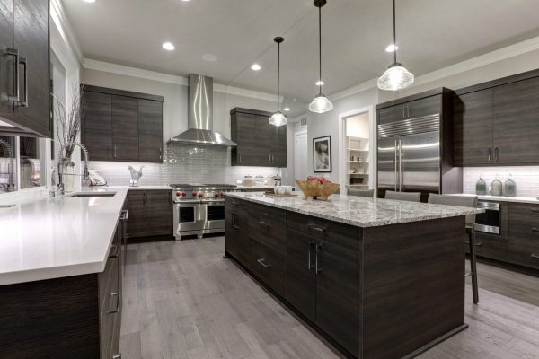Modern gray kitchen features dark gray flat front cabinets paired with white quartz countertops and a glossy gray linear tile backsplash. Northwest, USA.